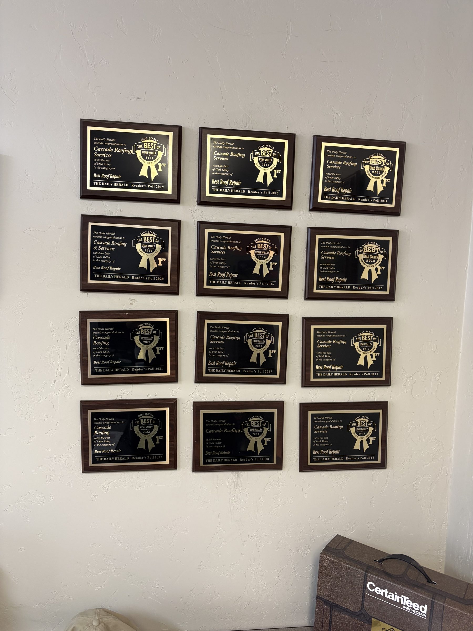 Twelve Daily Herald Readers' Choice plaques on the wall at Cascade Roofing